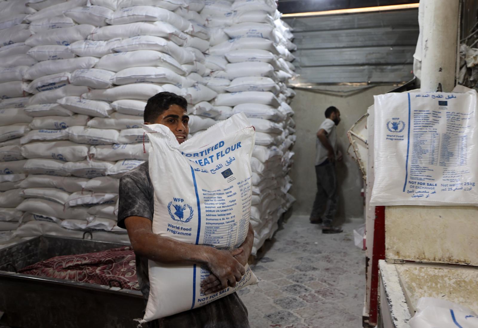 Workers moving flour bags